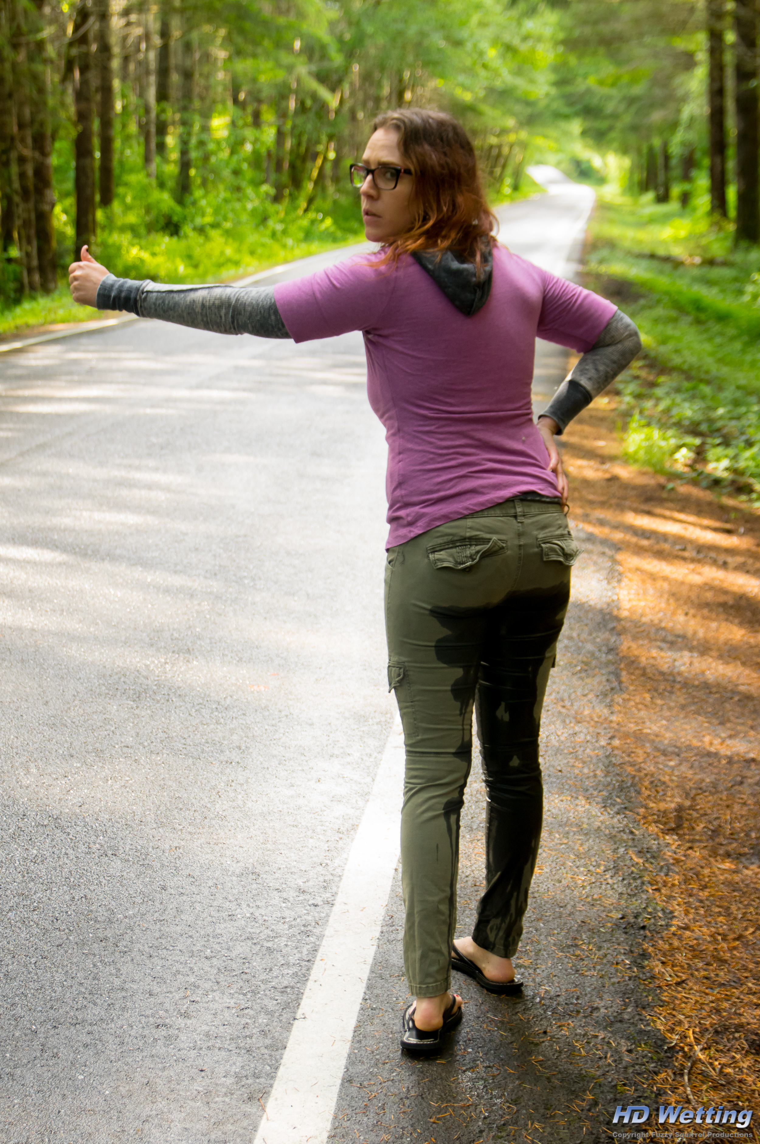 hitchhiking-3126 Rear view of Alisha along the highway after she has wet herself
