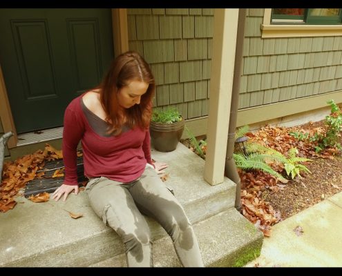 Alisha sits on her doorstep, having wet her pants, waiting for Sosha to show up with the spare key