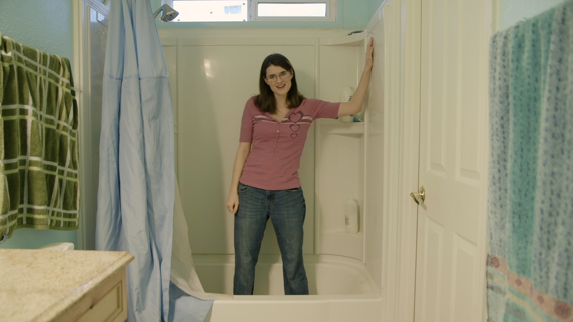 tub-1 Wearing a pink shirt and jeans, Sosha stands in the bath tub