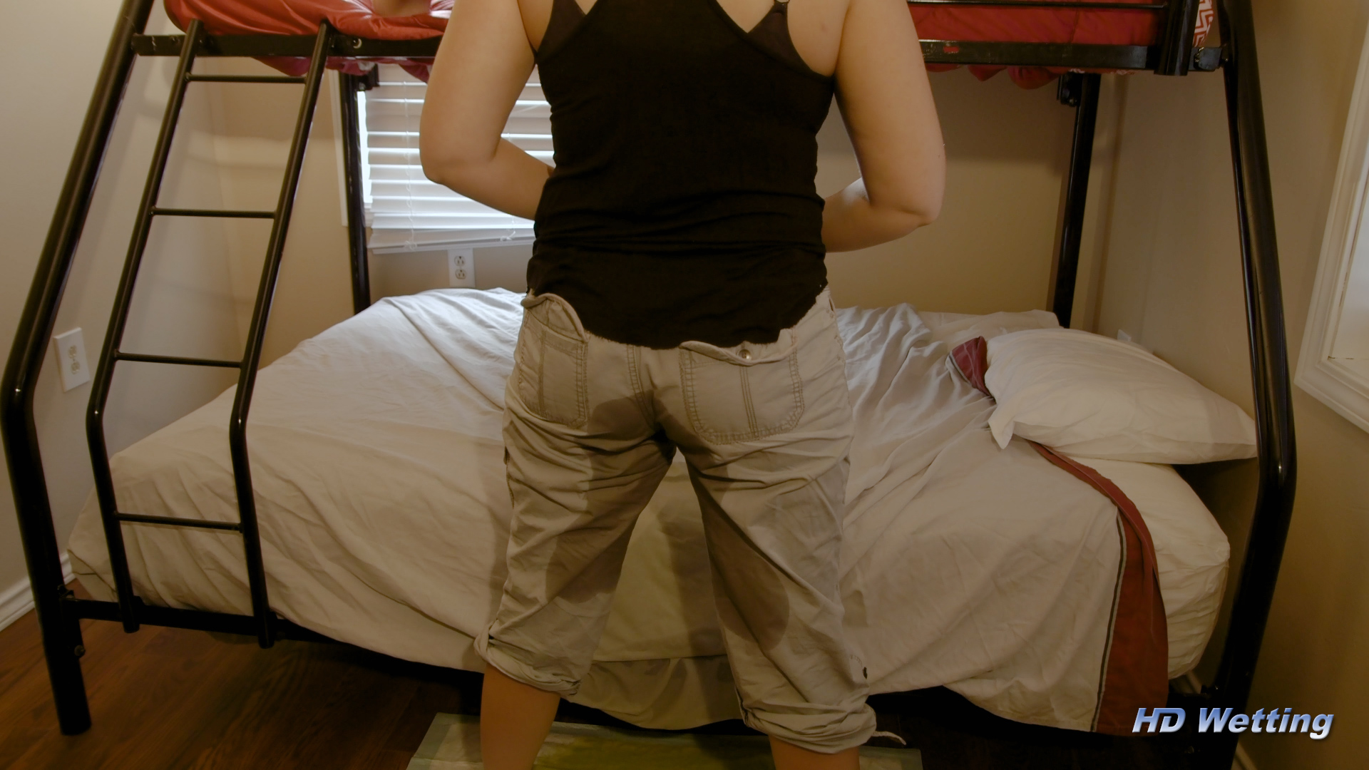 bed-6 Alisha stands next to the bed, facing away from the camera, showing us the back of her wet pants.