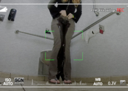 View through a hidden camera in a public bathroom of a girl wetting her pants.