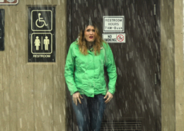 Sosha pees in her jeans in front of a public bathroom.
