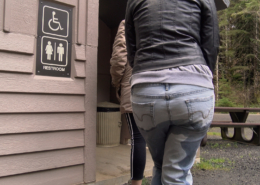 A woman wets her pants while waiting in line for a public toilet.